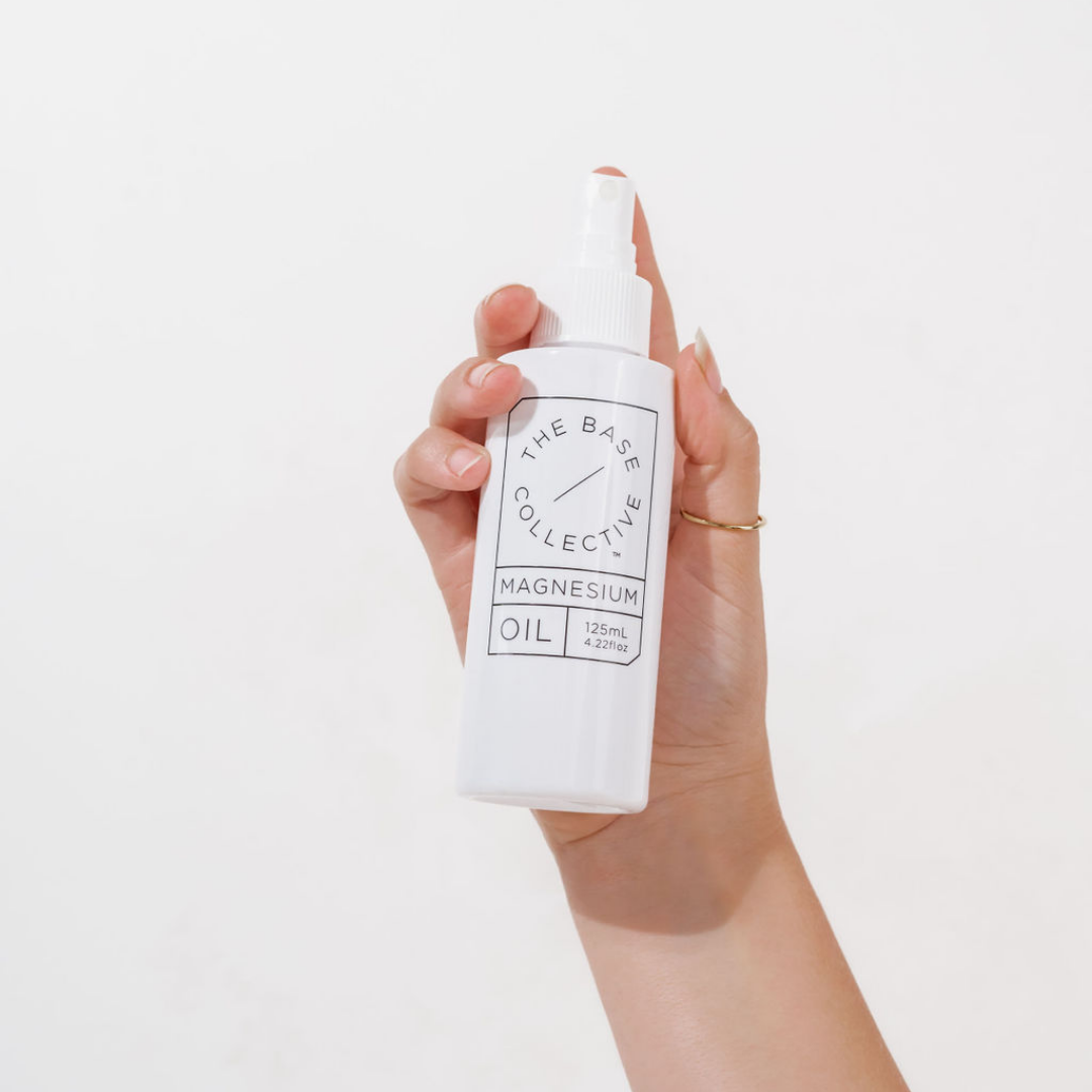 Magnesium Oil Spray by The Base Collective in hand on white background 