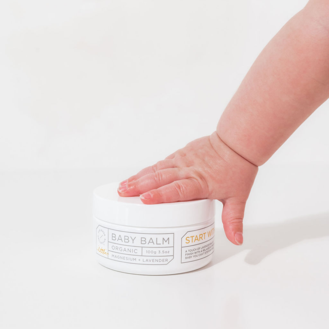 Magnesium lotion for kids by The Base Collective, baby hand on tub
