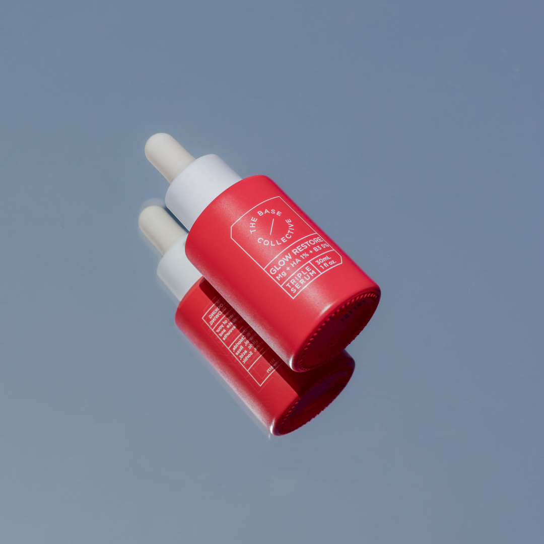 Dark Spot Correcting Serum aka Glow Niacinamide Serum with Hyaluronic Acid and Magnesium by The Base Collective on blue background with reflection