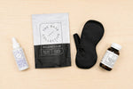 Collection of wellness products including a spray bottle, bag, eye mask, and jar on a beige background.