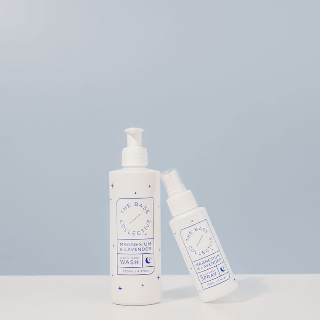 Magnesium Wash with Lavender and Magnesium Spray for Sleep leaning against it with a light blue background by The Base Collective 