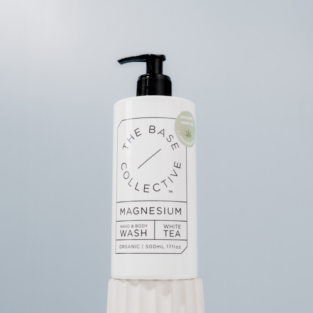 Lemongrass Body Wash by The Base Collective on white pillar against light blue background.