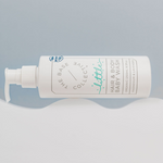 Little by The Base Collective Lavender Baby Wash on side with white cloud and blue background.